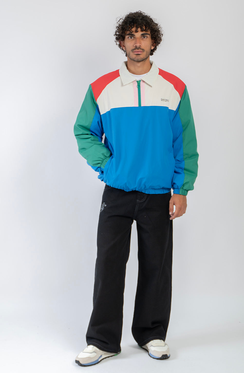Chaqueta Kangaroo color block azul, verde, rojo y marfil con media cremallera y logo Kaotiko Society.