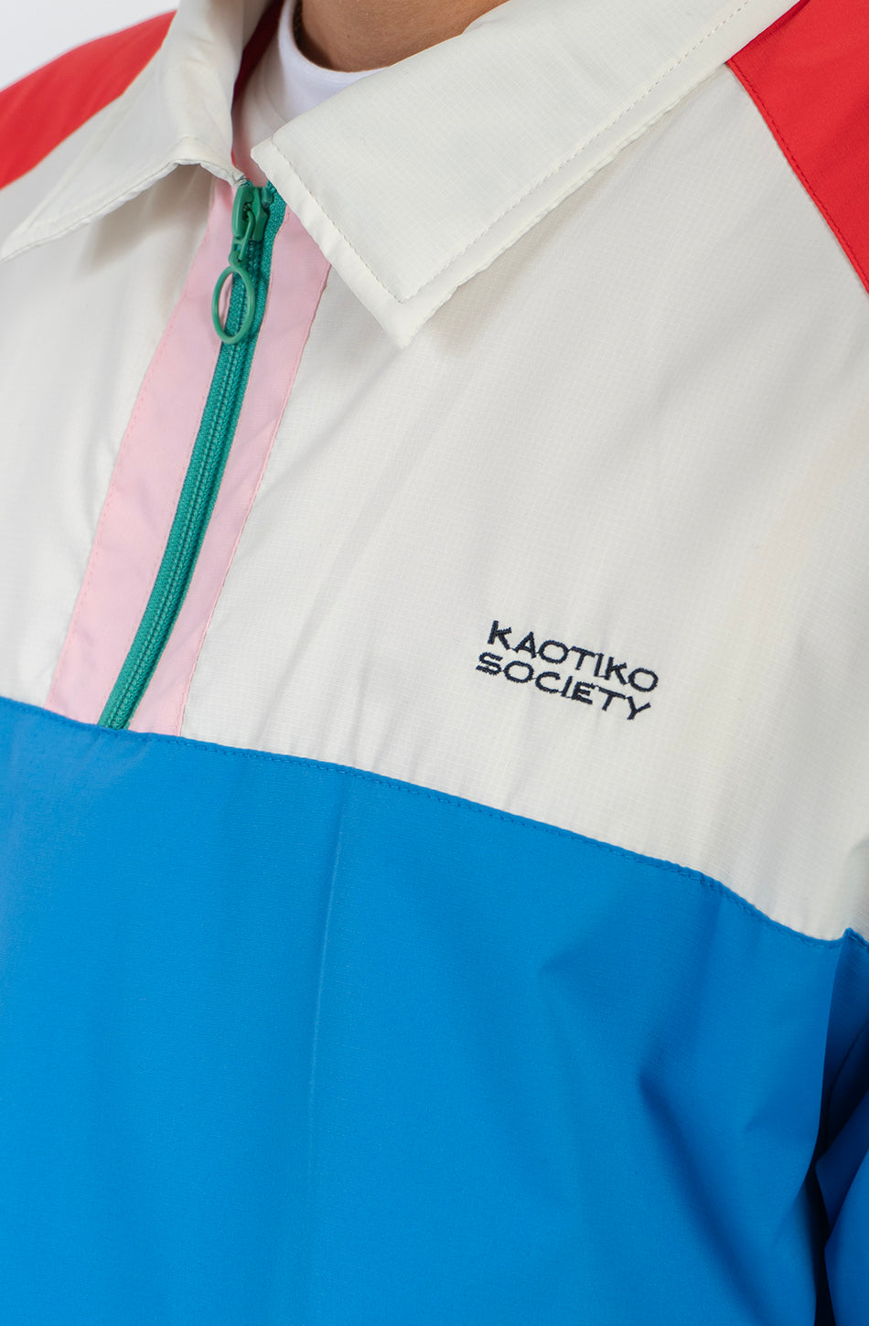 Chaqueta Kangaroo color block azul, verde, rojo y marfil con media cremallera y logo Kaotiko Society.