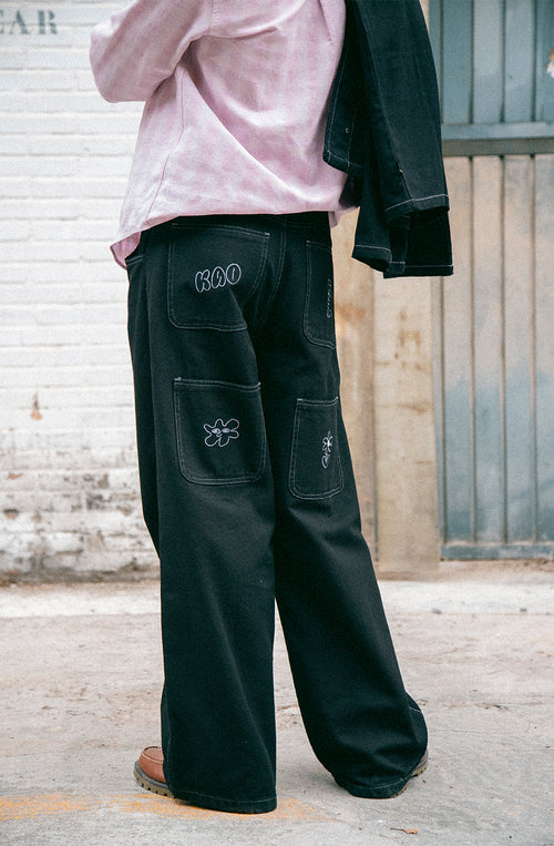 Pantalón unisex de denim negro con ilustraciones bordadas.
