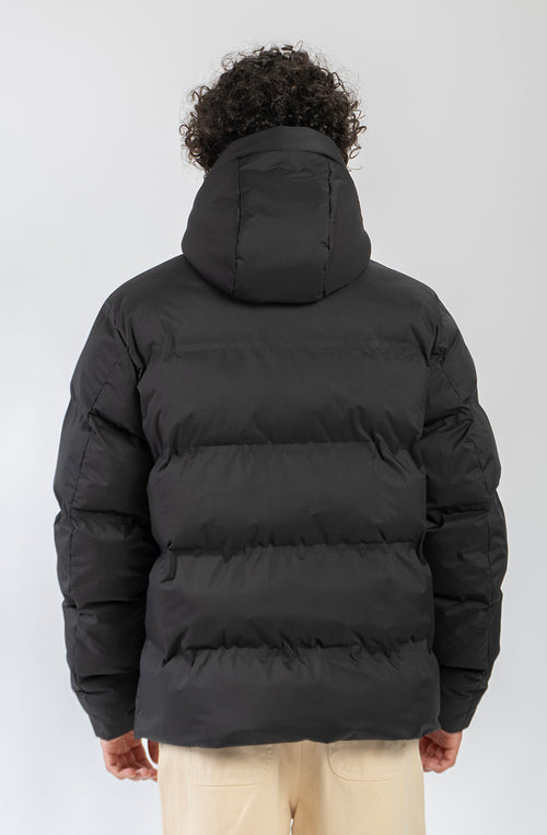 Chaqueta acolchada azul marino oscuro con capucha, cierre frontal y logo Kaotiko bordado en el pecho.