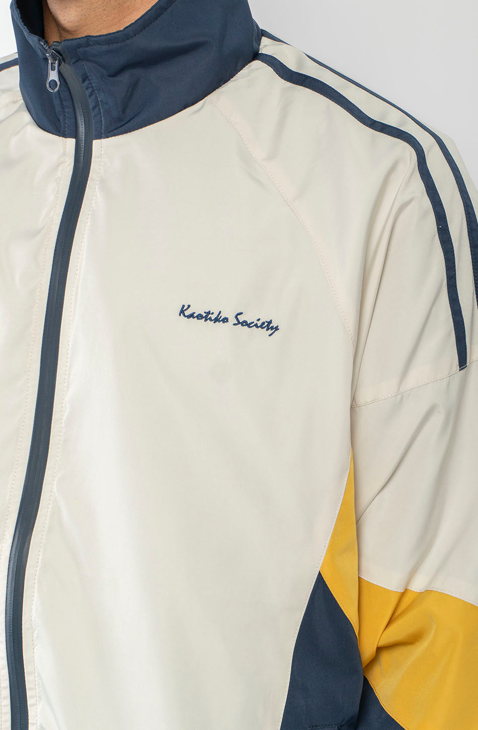 Chaqueta Retro Ski en marfil, vanilla y azul marino con diseño color block, cremallera a contraste y logo Kaotiko Society.